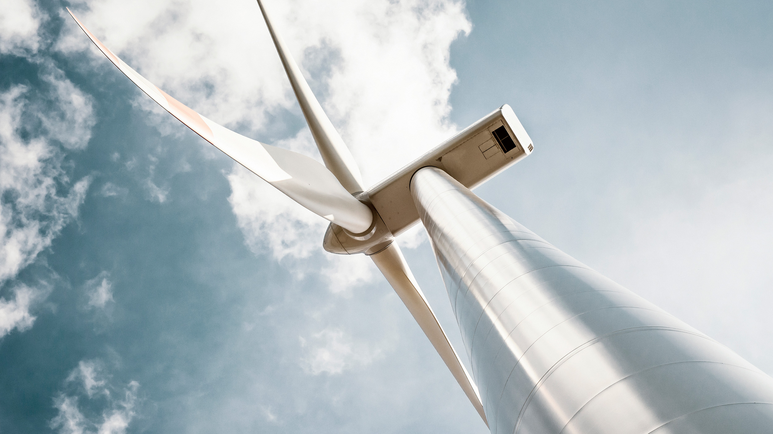 A close-up view of a wind turbine against a cloudy sky