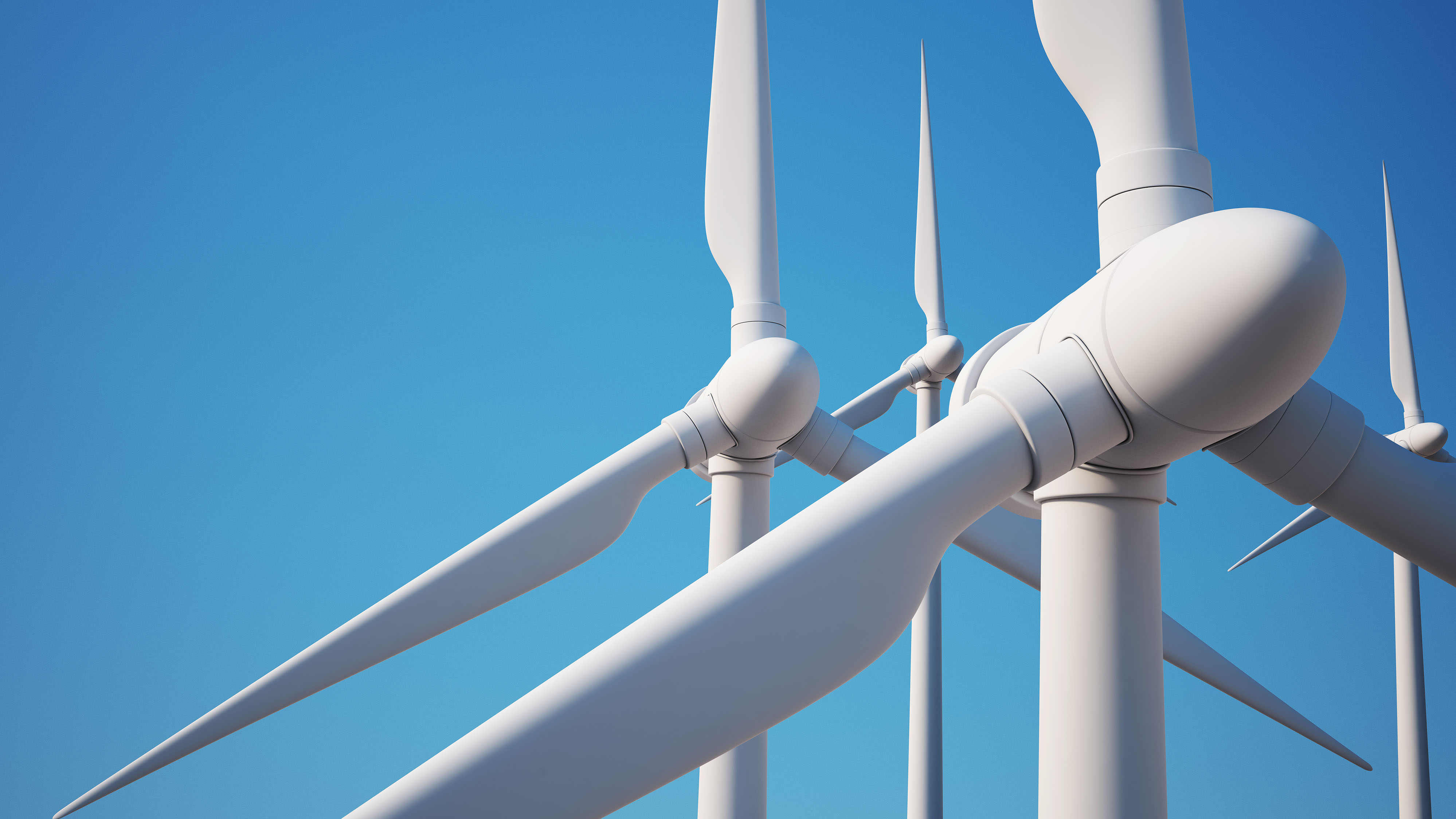 3 Wind turbines up close with blue sky in the background