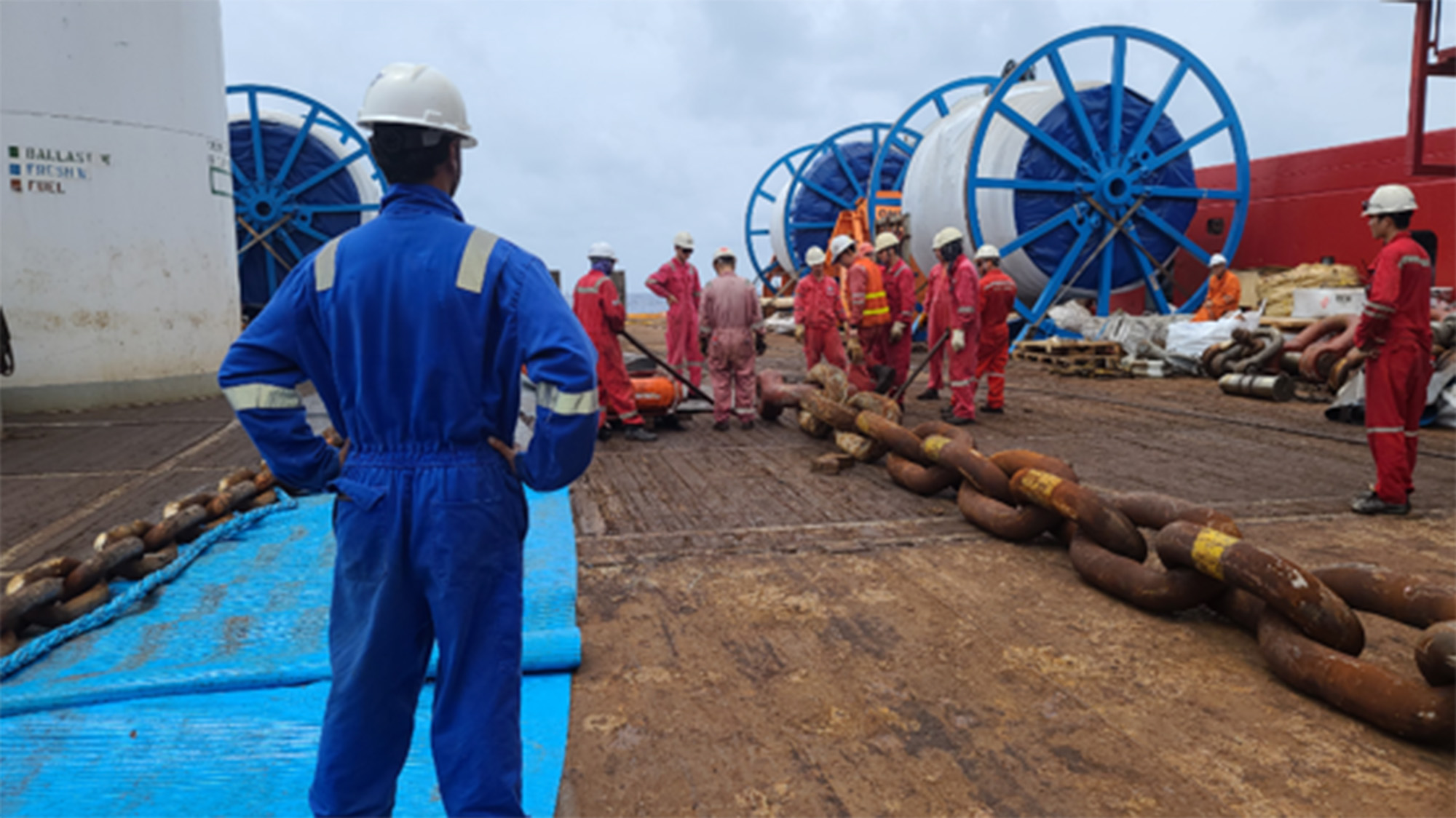 A man in blue coveralls on the deck of an anchor-handling vessel 