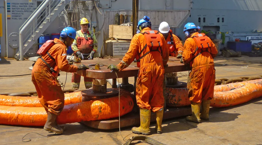Team of offshore guys in coveralls installing permanent mooring rope 