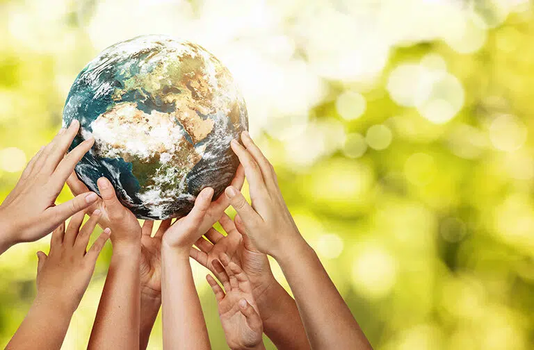 Group of children holding planet earth over defocused nature background