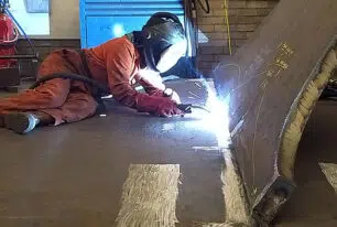 man welding plates of steel to make an anchor