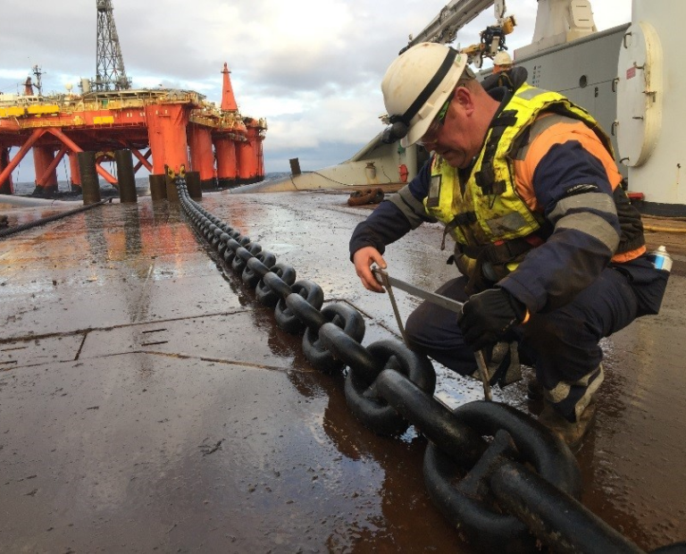 Man inspecting mooring chain with calipers